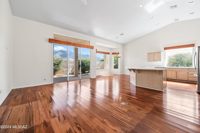 unfurnished living room with a mountain view, lofted ceiling, hardwood / wood-style floors, and a healthy amount of sunlight