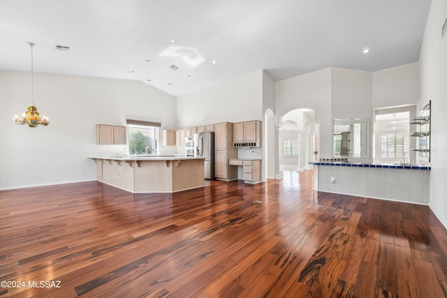 unfurnished living room featuring a notable chandelier, dark hardwood / wood-style flooring, and high vaulted ceiling