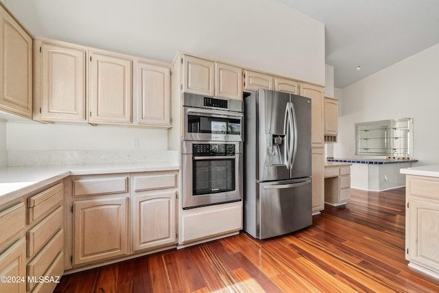 kitchen featuring appliances with stainless steel finishes, lofted ceiling, and hardwood / wood-style floors