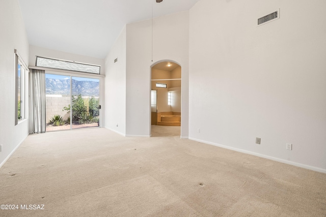 unfurnished room with light colored carpet and high vaulted ceiling