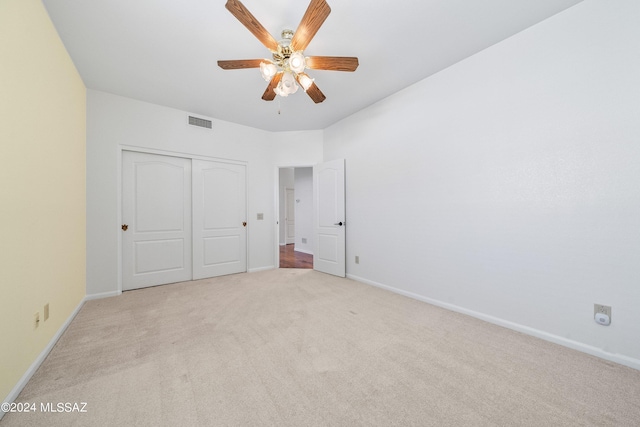 unfurnished bedroom with light carpet, ceiling fan, and a closet