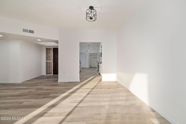 corridor featuring light hardwood / wood-style floors and an inviting chandelier