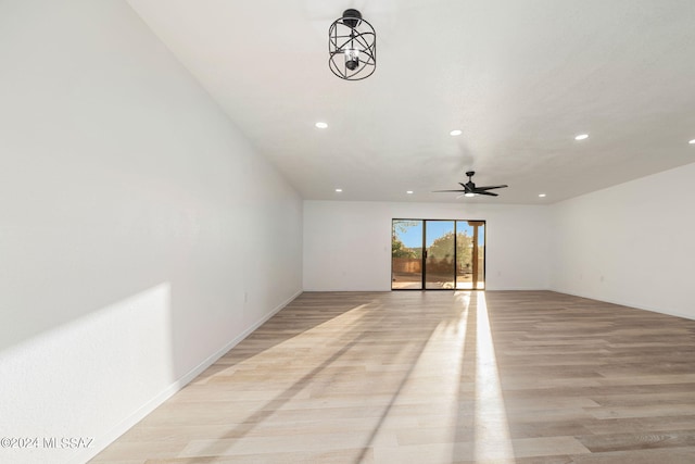 unfurnished room with ceiling fan with notable chandelier and light wood-type flooring