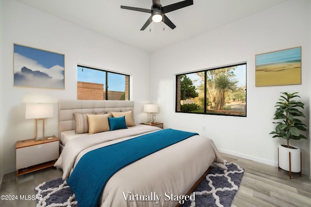 bedroom featuring hardwood / wood-style floors, ceiling fan, and multiple windows