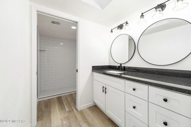 bathroom with tiled shower, wood-type flooring, and vanity