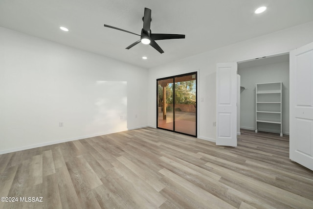 unfurnished bedroom with access to exterior, a spacious closet, light hardwood / wood-style flooring, and ceiling fan