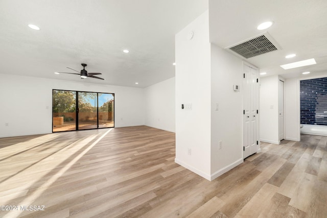 interior space with ceiling fan, light wood-type flooring, and a skylight