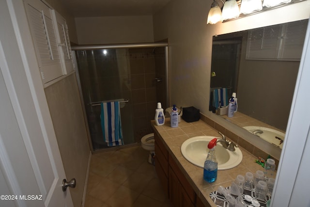 bathroom with tile patterned flooring, a shower with door, vanity, and toilet