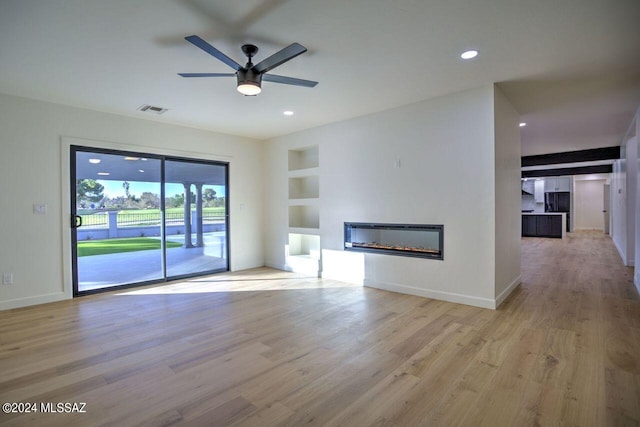 unfurnished living room with ceiling fan, built in features, and light hardwood / wood-style floors