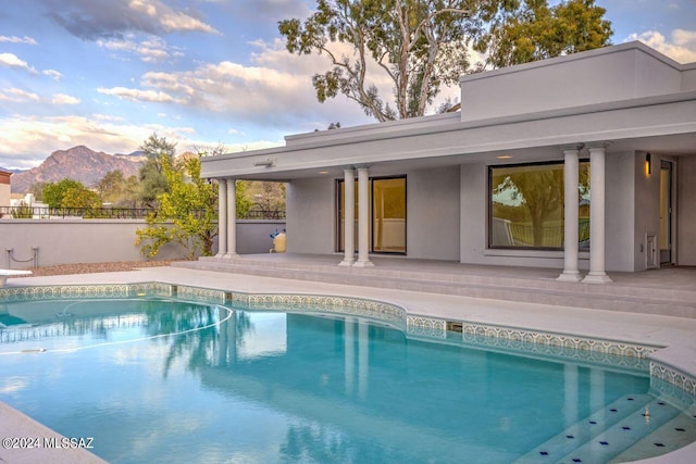 pool at dusk featuring a mountain view