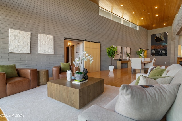 living room with light carpet, a towering ceiling, a barn door, and wooden ceiling