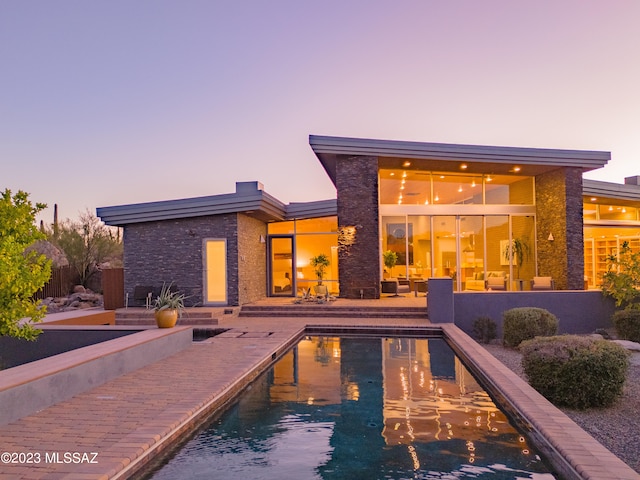 pool at dusk featuring a patio area