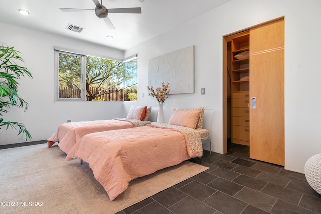 bedroom featuring a spacious closet, a closet, ceiling fan, and dark tile patterned floors