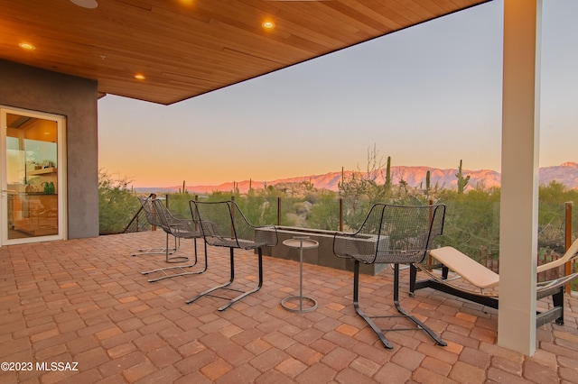 patio terrace at dusk featuring a mountain view