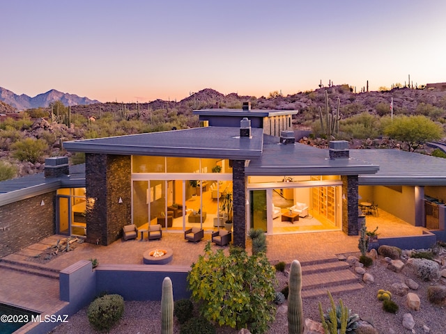 back house at dusk featuring a mountain view and a patio area