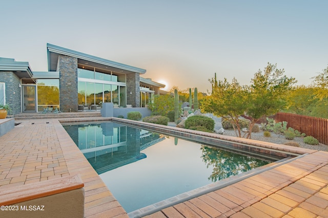 pool at dusk with a patio area