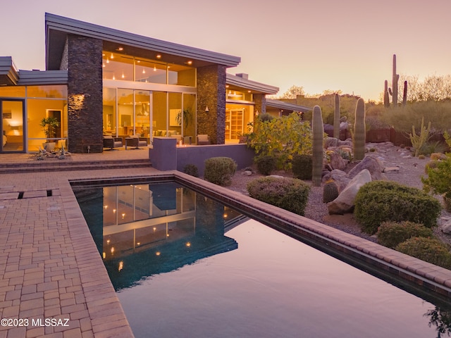 pool at dusk featuring a patio and an outdoor living space