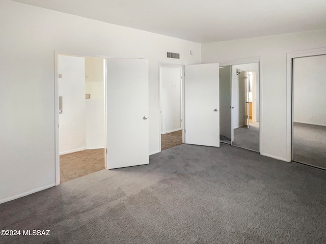 unfurnished bedroom featuring dark colored carpet and ensuite bath