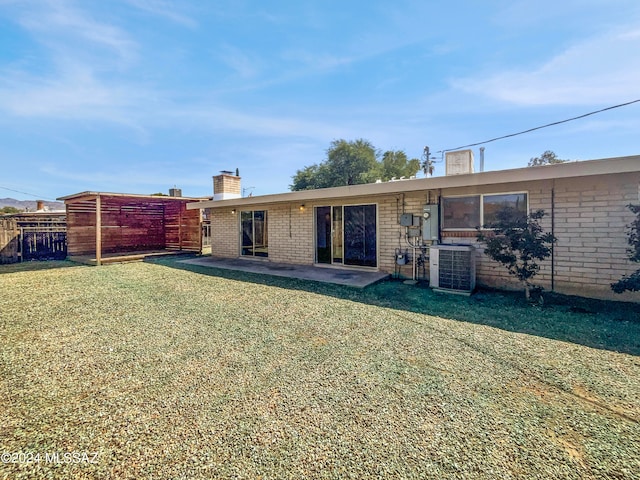 rear view of property featuring a patio area, cooling unit, and a lawn