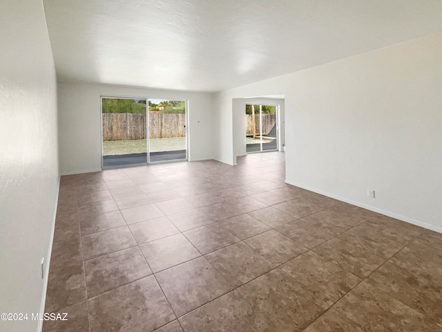 tiled spare room with lofted ceiling