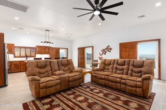 living room featuring light wood-type flooring, sink, and ceiling fan