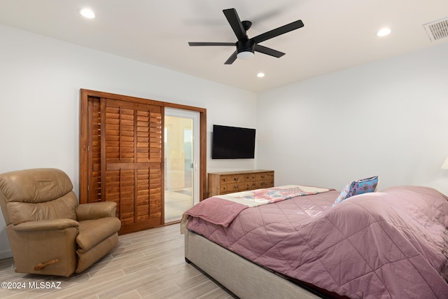 bedroom with light hardwood / wood-style floors, ceiling fan, and ensuite bath