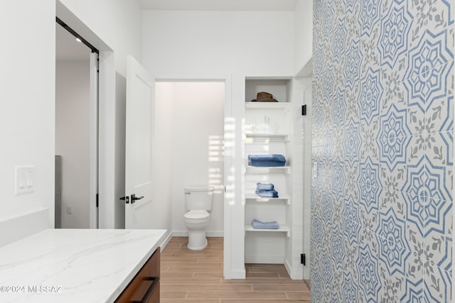 bathroom with walk in shower, vanity, hardwood / wood-style flooring, and toilet