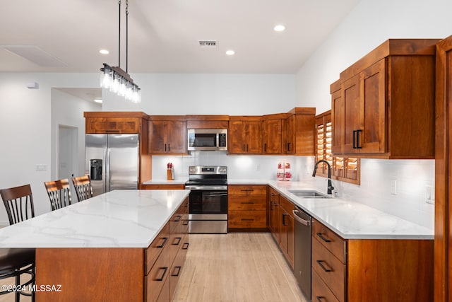 kitchen featuring a kitchen island, light wood-type flooring, appliances with stainless steel finishes, a kitchen bar, and sink