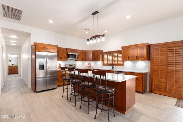 kitchen with pendant lighting, light wood-type flooring, appliances with stainless steel finishes, and a center island