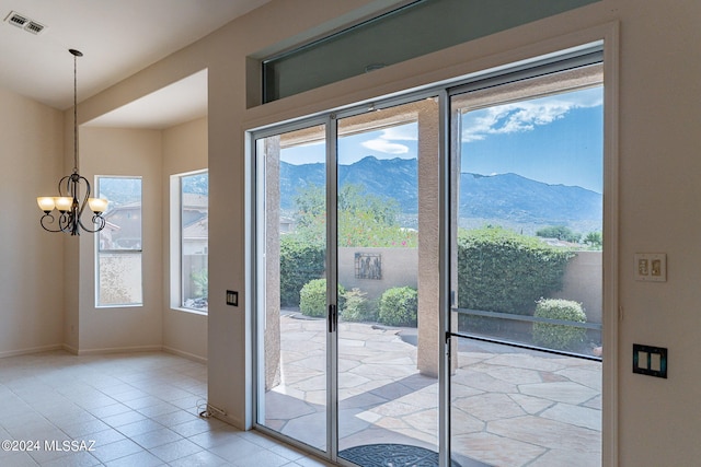 doorway with an inviting chandelier, a wealth of natural light, a mountain view, and light tile patterned floors