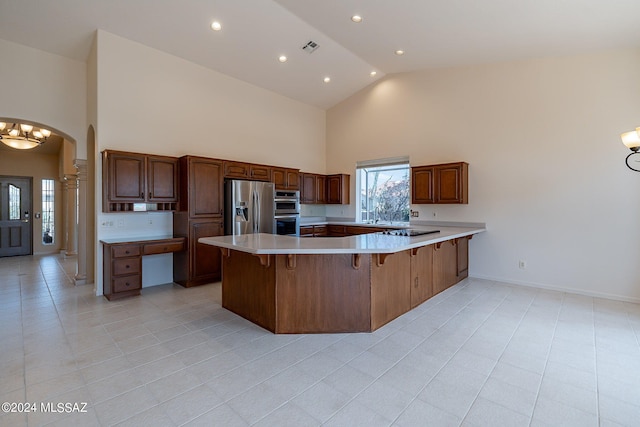 kitchen with light tile patterned floors, kitchen peninsula, high vaulted ceiling, appliances with stainless steel finishes, and a breakfast bar area