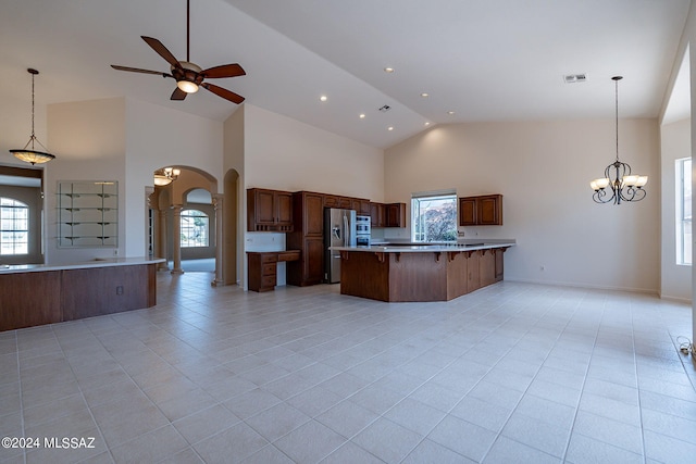 kitchen with light tile patterned flooring, a large island, high vaulted ceiling, and decorative light fixtures