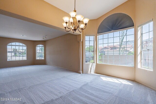 carpeted empty room with an inviting chandelier and a wealth of natural light