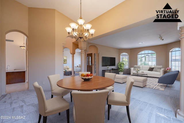 carpeted dining space featuring a chandelier and ornate columns