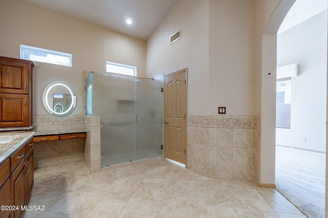 bathroom with high vaulted ceiling, a shower with door, and vanity