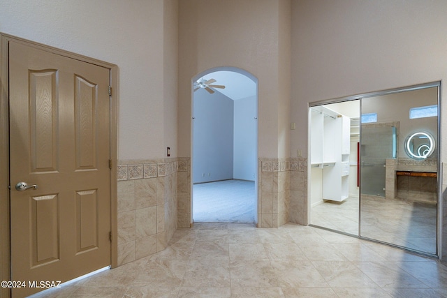 interior space with light tile patterned flooring, tile walls, and a towering ceiling