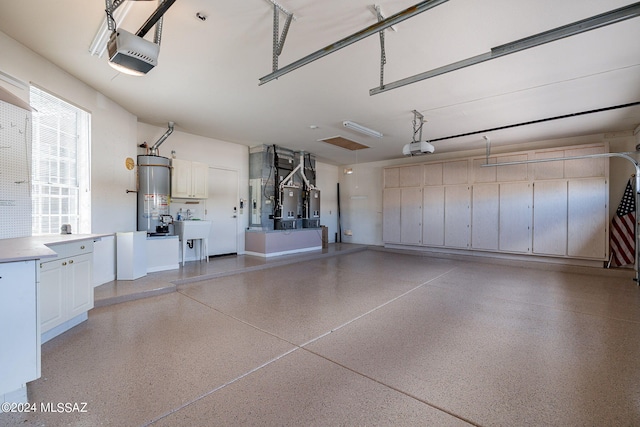 garage featuring gas water heater, heating unit, a garage door opener, and sink