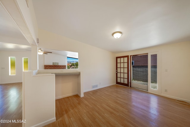 unfurnished living room with ceiling fan, light hardwood / wood-style floors, french doors, and vaulted ceiling