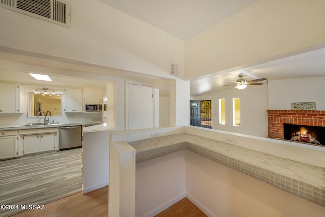 kitchen with white cabinetry, sink, stainless steel appliances, light hardwood / wood-style flooring, and kitchen peninsula