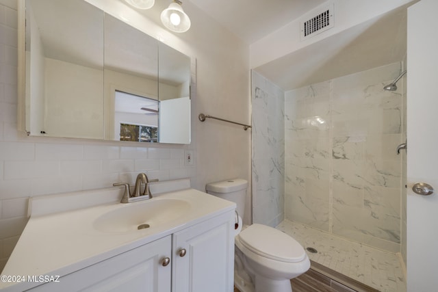 bathroom with a tile shower, backsplash, hardwood / wood-style floors, toilet, and vanity