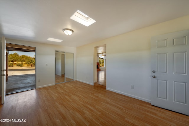 unfurnished room with light wood-type flooring and a skylight