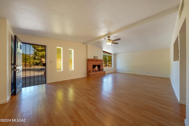 unfurnished living room with a fireplace, lofted ceiling with beams, hardwood / wood-style flooring, and ceiling fan