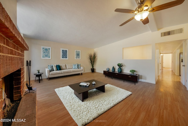 living room with hardwood / wood-style floors, vaulted ceiling with beams, a brick fireplace, and ceiling fan