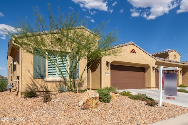 view of front of home featuring a garage, concrete driveway, a tiled roof, and stucco siding