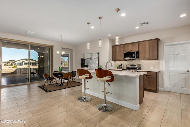 kitchen featuring stainless steel appliances, visible vents, light countertops, tasteful backsplash, and pendant lighting