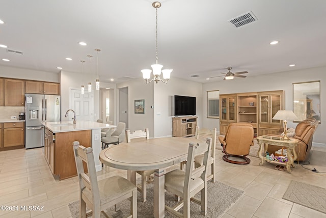 dining space with ceiling fan with notable chandelier and sink