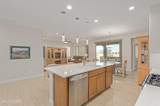 kitchen with pendant lighting, sink, an island with sink, ceiling fan with notable chandelier, and appliances with stainless steel finishes