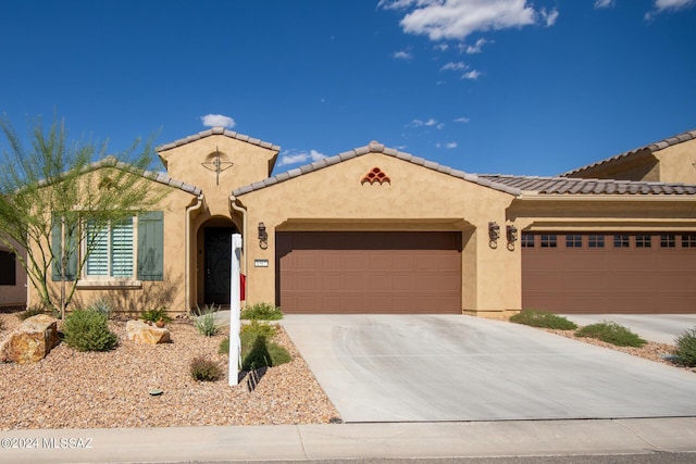 mediterranean / spanish home featuring driveway, a tile roof, a garage, and stucco siding