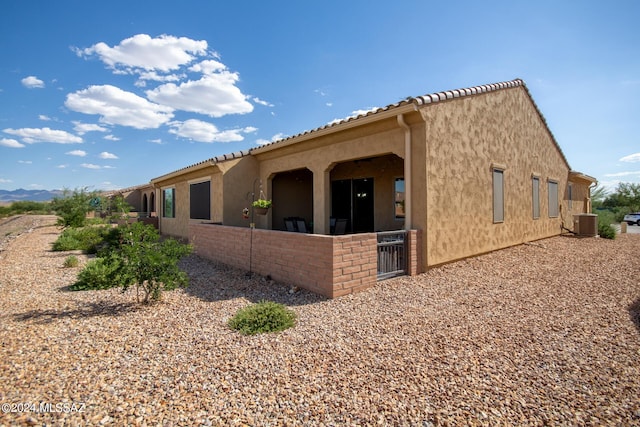 view of home's exterior featuring a tile roof, cooling unit, and stucco siding