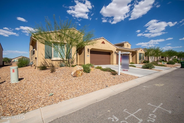 view of front of home with a tiled roof, an attached garage, driveway, and stucco siding